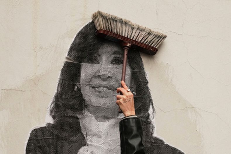Una partidaria de la expresidenta argentina Cristina Fernández utiliza una escoba para pegar una foto suya en un muro delante de su casa después de que el Supremo del país respaldara la condena de corrupción de Fernández, en Buenos Aires, Argentina, el martes 17 de junio de 2025. (AP Foto/Natacha Pisarenko)