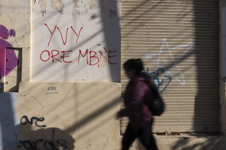 Una mujer pasa junto a un grafiti en guaraní que dice yvy ore mbae, que significa La tierra es nuestra, en Asunción, Paraguay, el viernes 22 de agosto de 2025. (AP Foto/Jorge Saenz)