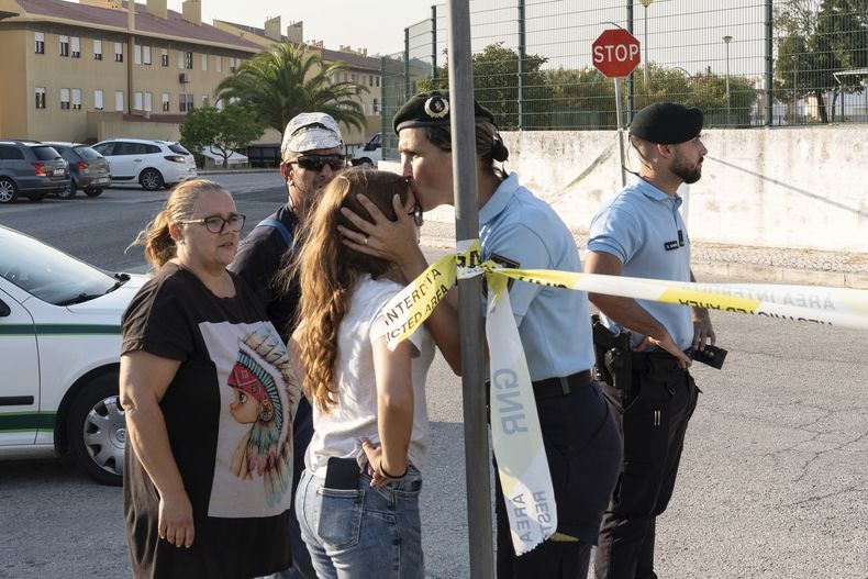 Una policía besa a una niña afuera de una escuela donde un niño hirió a puñaladas a otros niños en Azambuja, cerca de Lisboa, el 17 de septiembre de 2024. (Foto AP /Ana Brigida)