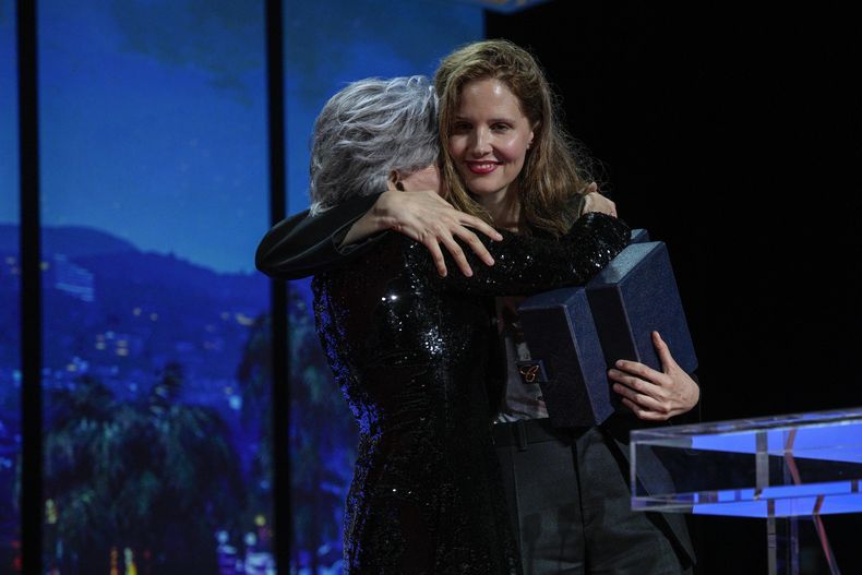 La directora de cine Justine Triet (derecha) abraza a Jane Fonda al aceptar la Palma de Oro por la cinta Anatomie dune chute durante la ceremonia de premiación del 76° festival internacional de cine de Cannes, Francia, el sábado 27 de mayo de 2023. (AP Foto/Daniel Cole)