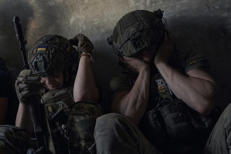 Soldados ucranianos cubren sus oídos para protegerse del bombardeo ruso en un refugio en el frente en la región de Zaporiyia, Ucrania, el domingo 2 de julio de 2023. (AP Foto/Libkos)