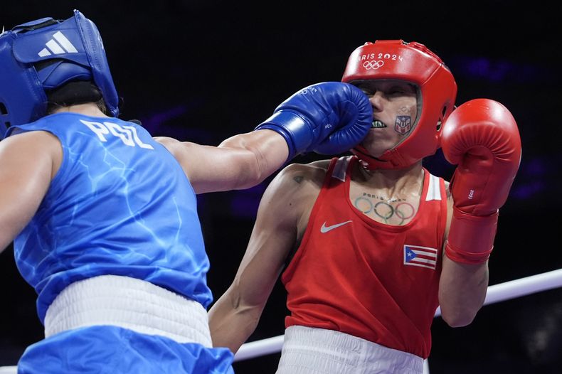 La polaca Julia Szeremeta, de azul, golpea a la puertorriqueña Ashleyann Lozada en su combate de cuartos de final de peso ligero del torneo olímpico, el domingo 4 de agosto de 2024, en Villepinte, Francia. (AP Foto/Ariana Cubillos)
