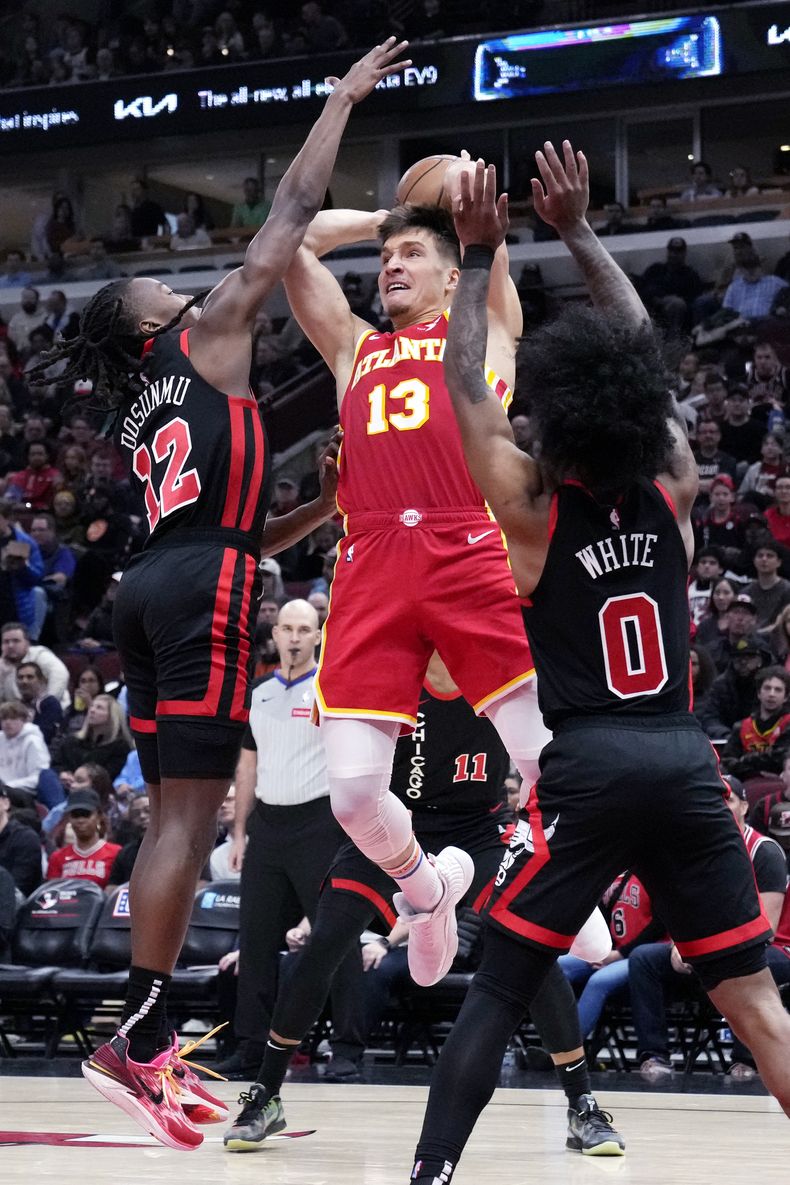 El escolta de los Hawks de Atlanta, Bogdan Bogdanovic, centro, busca pasar mientras el escolta de los Bulls de Chicago, Ayo Dosunmu, izquierda, y el escolta Coby White, escolta, durante la primera mitad de un partido de baloncesto de la NBA en Chicago, el lunes 1 de abril de 2024. (AP Foto/Nam Y. Huh)