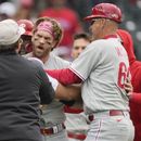 Bryce Harper, centro, de los Filis de Filadelfia, es contenido por el umpire de primera, Ben May, izquierda, y el coach de tercera de los Filis, Dusty Wathan, después de reaccionar a una burla del relevista de los Rockies de Colorado, Jake Bird, en la séptima entrada del juego de béisbol, el domingo 14 de mayo de 2023, en Denver. (AP Foto/David Zalubowski)
