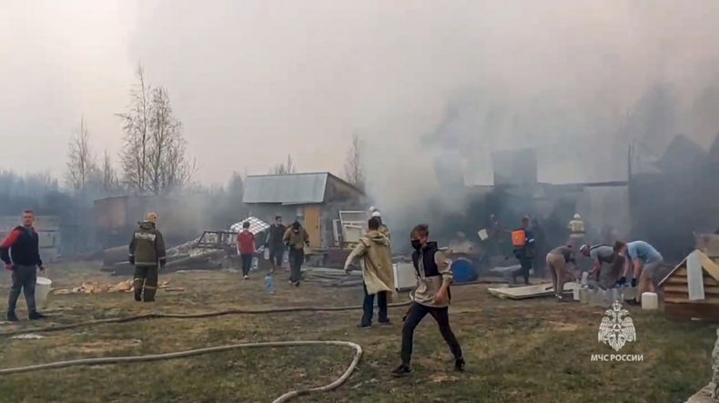 En esta fotografía proporcionada por el Servicio de Prensa del Ministerio de Situaciones de Emergencia de Rusia el lunes 8 de mayo de 2023, empleados del ministerio y habitantes locales trabajan en el sitio donde se registró un incendio forestal, en la región de Tiumén, Rusia. (Servicio de Prensa del Ministerio de Situaciones de Emergencia de Rusia vía AP)