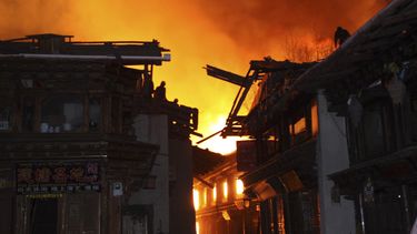 americateve | Bomberos combaten el incendio desde los techos de los edificios mientras las llamas destruyen el milenario poblado tibetano de Dukezong en el condado Shangri-La, en el suroeste de China, el s&aacute;bado 11 de enero de 2014. (Foto AP)