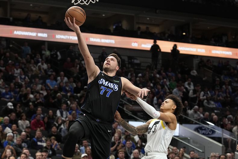 Luka Doncic (77), de los Mavericks de Dallas, deja atrás a Keyonte George (3), del Jazz de Utah, mientras se alista a encestar una canasta durante la segunda mitad del juego de baloncesto de la NBA, en Dallas, el miércoles 6 de diciembre de 2023. (AP Foto/LM Otero)