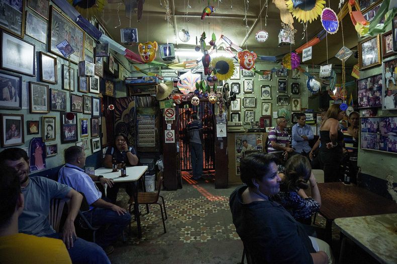 Los clientes pasan tiempo en el bar Las Delicias en el barrio La Pastora de Caracas, Venezuela, el viernes 2 de junio de 2023. Las Delicias es parte de la Ruta de los Templos Paganos, organizada para atraer nuevos clientes a ocho tabernas históricas en la capital de Venezuela. (Foto AP/Juan Pablo Arráez)