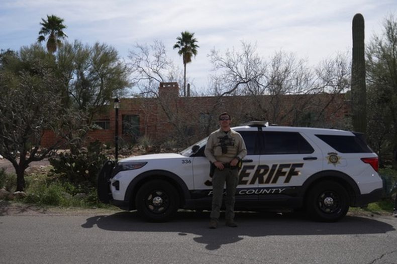 Un miembro de la policía del condado Pima se ve junto a su vehículo ante la casa de Nancy Guthrie el martes 10 de febrero de 2026 en Tucson, Arizona. (AP Foto/Ty ONeil)