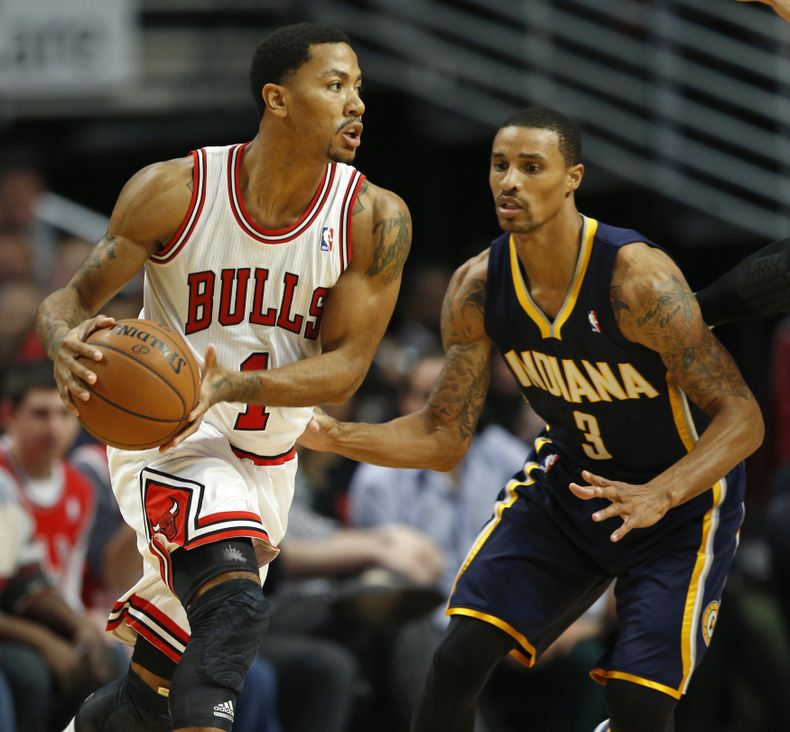 Derrick Rose, de los Bulls de Chicago, busca enviar un pase frente a George Hill, de los Pacers de Indiana, en el partido del s&aacute;bado 16 de noviembre de 2013 (AP Foto/Kamil Krzaczynski)