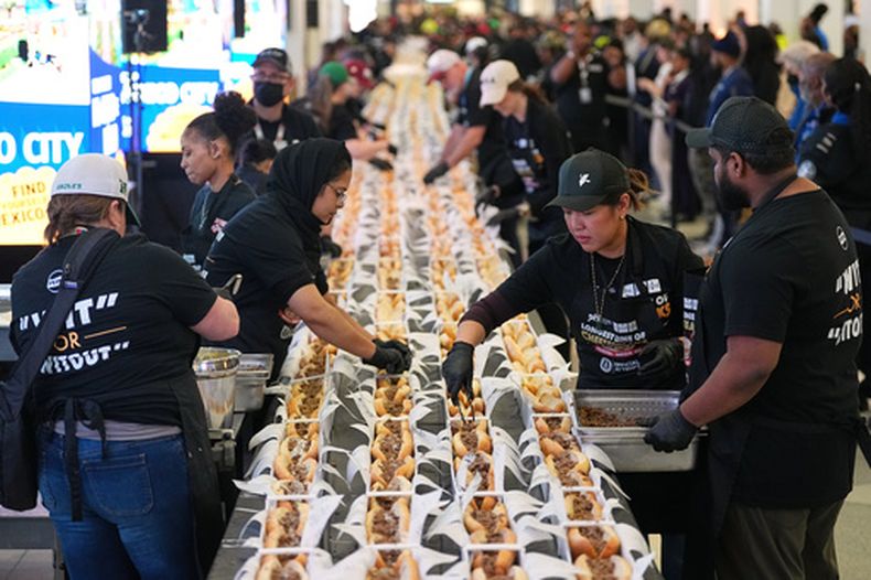 Un grupo de voluntarios preparan cheesesteaks en un intento de lograr un récord Guinness en el Día Nacional del Cheesesteak en el Aeropuerto Internacional de Filadelfia, el martes 24 de marzo de 2026, en Filadelfia. (AP Foto/Matt Rourke)