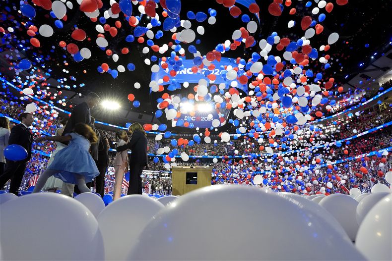 La vicepresidenta y candidata demócrata a la presidencia, Kamala Harris, el segundo caballero Doug Emhoff, el candidato demócrata a la vicepresidencia, el gobernador de Minnesota Tim Walz y su esposa Gwen Walz y miembros de sus familias suben al escenario mientras caen globos en la última noche de la Convención Nacional Demócrata en Chicago. Jueves 22 de agosto de 2024. (Kent Nishimura/The New York Times vía AP, Pool)