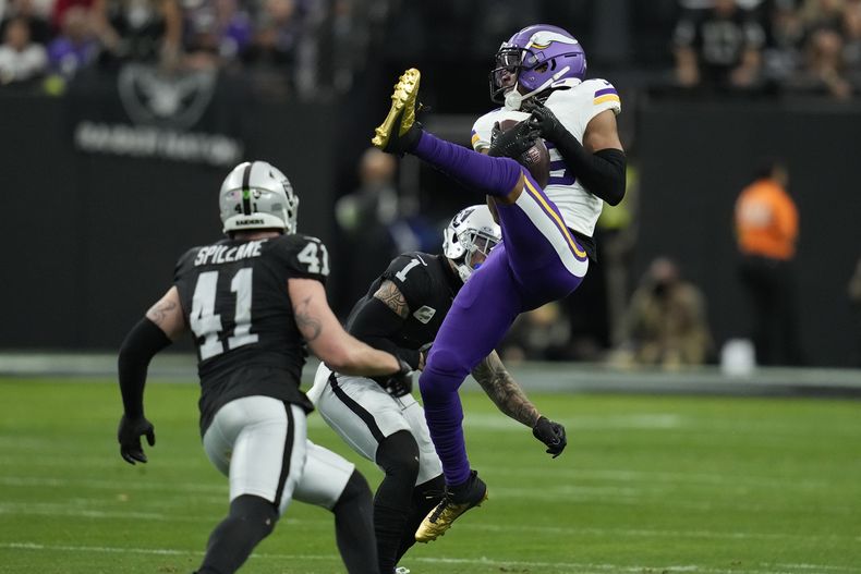 El wide receiver de los Vikings de Minnesota Justin Jefferson (18) realiza una atrapada mientras defiende el safety de los Raiders de Las Vegas Marcus Epps (1) durante la primera mitad del juego de la NFL, el domingo 10 de diciembre de 2023, en Las Vegas. (AP Foto/John Locher)
