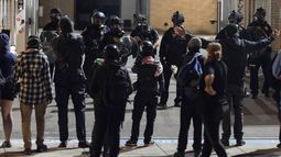 Manifestantes gritan a los policías al regresar a las puertas de acceso luego que los agentes crearon un camino para que vehículos salieran del edificio del Servicio de Inmigración y Control de Aduanas de Estados Unidos (ICE, por sus siglas en inglés) en Portland, Oregon, el miércoles 10 de septiembre de 2025. (AP Foto/Jenny Kane)