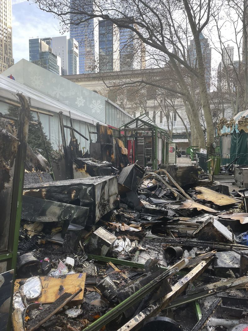 Esta imagen proporcionada por el Departamento de Bomberos de Nueva York (FDNY, por sus siglas en inglés), trabajadores del departamento investigan las secuelas de un incendio en un mercado navideño al aire libre en Bryant Park, Nueva York, ocurrido el viernes 27 de diciembre de 2024. (FDNY vía AP)