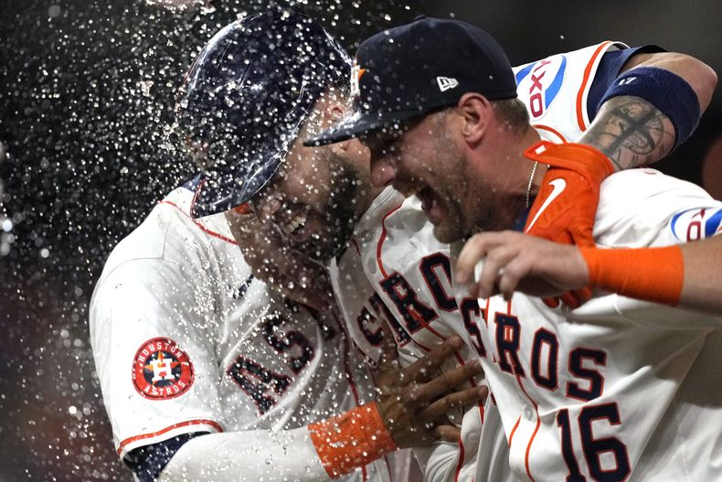 El puertorriqueño Víctor Caratini (centro) festeja con Grae Kessinger (16) y con el dominicano Jeremy Peña, sus compañeros en los Astros de Houston, tras la victoria sobre los Atléticos de Oakland, el martes 14 de mayo de 2024 (AP Foto/David J. Phillip)