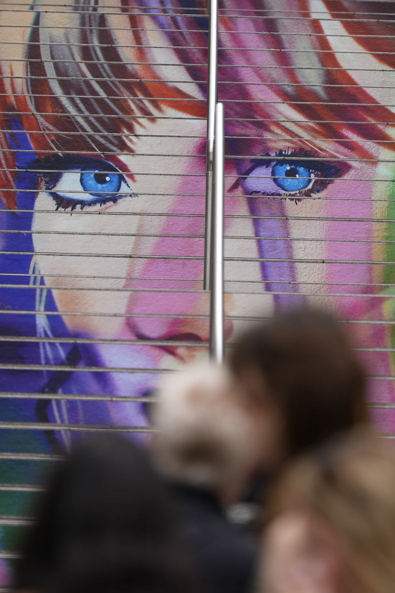 Fans posan frente a un retrato de Taylor Swift pintado en una escalera en el estadio de Wembley en Londres, el miércoles 14 de agosto de 2024, antes de una serie de conciertos de Taylor Swift que comienzan el jueves. (Foto AP/Alastair Grant)