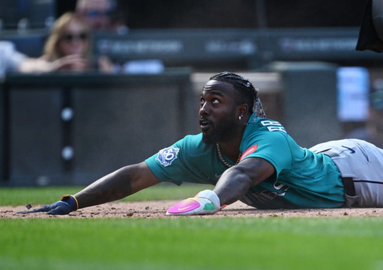 Randy Arozarena, de los Marineros de Seattle, observa a un compañero de equipo después de llegar barrido al plato a salvo en la cuarta entrada del juego de béisbol de Grandes Ligas contra los Rockies de Colorado, el domingo 20 de septiembre de 2026, en Denver. (AP Foto/RJ Sangosti)