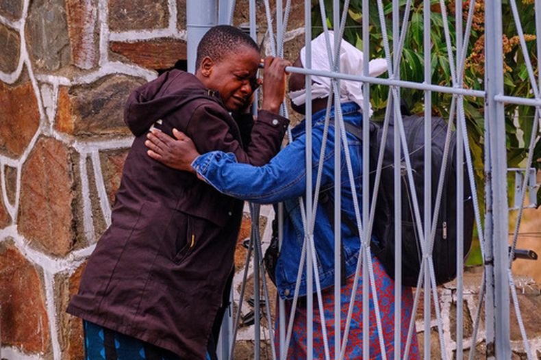 Un colega abraza a Philis Hamandise, centro, en la puerta de un centro de identificación de víctimas tras perder a su hija de 9 años y su sobrino de 6 en el naufragio de un ferry en el lago Kariba, en Kariba, Zimbabue, el jueves 13 de agosto de 2026. (AP Foto/Mkhululi Thobela)