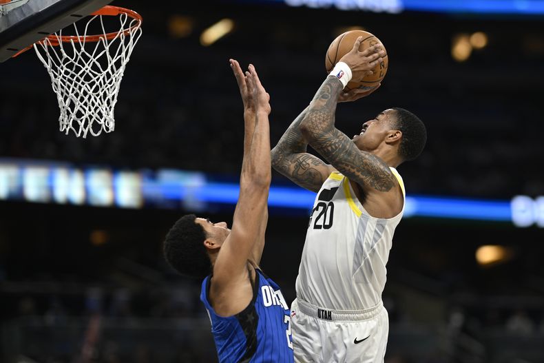 El alero del Jazz de Utah John Collins (20) tira mientras el escolta del Magic de Orlando Caleb Houstan (2) defiende durante la segunda mitad del partido de baloncesto de la NBA, el jueves 29 de febrero de 2024, en Orlando, Florida (AP Foto/Phelan M. Ebenhack)