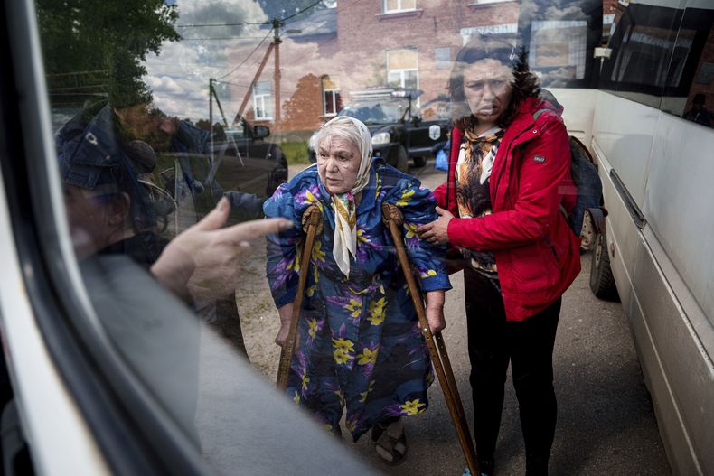 Una mujer ayuda a Liudmila, de 85 años, a abordar un autobús el 12 de mayo de 2024 tras ser evacuada de Vovchansk, Ucrania. Su esposo murió en su casa durante un bombardeo ruso sobre la ciudad. (AP Foto/Evgeniy Maloletka)