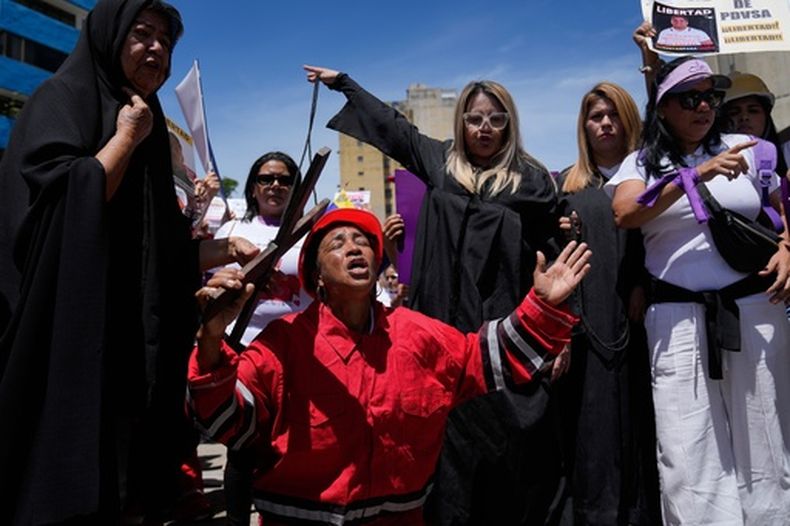 Luisa Delcine, en el centro, recrea el Vía Crucis para protestar por la detención y el encarcelamiento de su hijo Luis frente a la Corte Suprema en Caracas, Venezuela, el viernes 20 de marzo de 2026. Delcine afirmó que su hijo fue encarcelado en 2024 en relación con el Caso Obrero de PDVSA, pero que ni ella ni su hijo trabajaban para la petrolera estatal. (Foto AP/Ariana Cubillos)