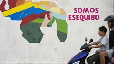 Un niño conduce una motocicleta por delante de un mural con el mapa de Venezuela, que incluye el territorio de Esequibo, en el vecindario 23 de Enero de Caracas, Venezuela, el 11 de diciembre de 2023. (AP Foto/Matías Delacroix)