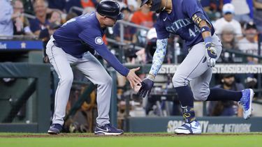 El coach de tercera base de los Marineros de Seattle, Manny Acta, izquierda, y Julio Rodriguez, derecha, celebran jonrón de dos carreras del dominicano en contra de los Astros de Houston, durante la novena entrada del juego de béisbol del miércoles 25 de septiembre de 2024, en Houston. (AP Foto/Michael Wyke)