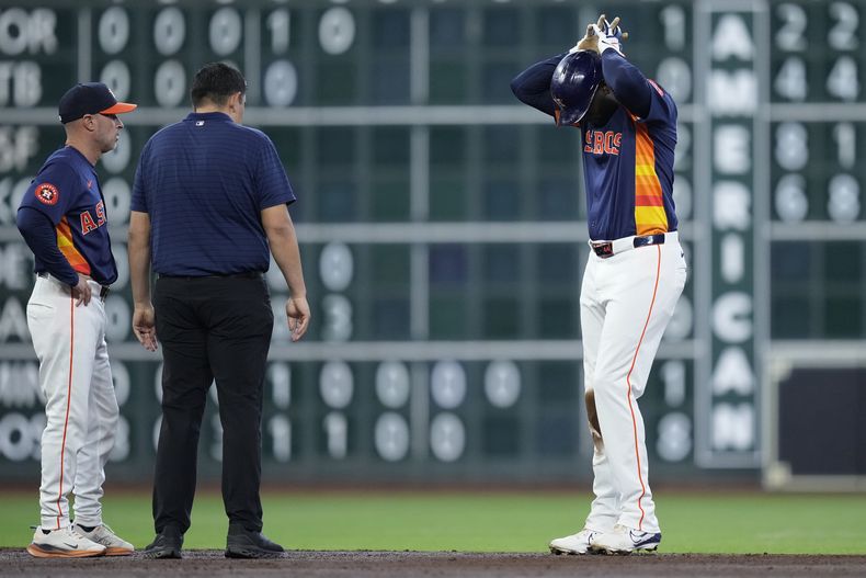 Yordan Álvarez, derecha, de los Astros de Houston, prueba su pierna derecha ante la mirada del mánager Joe Espada, izquierda, y un miembro del cuerpo médico del equipo después de sufrir una lesión al barrerse en segunda base durante la tercera el juego de béisbol en contra de los Angelinos de Los Ángeles, el domingo 22 de septiembre de 2024. (AP Foto/Kevin M. Cox)