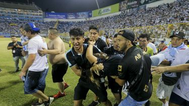 Un grupo de hinchas carga a un aficionado herido hacia la cancha del estadio de Cuscatlán en San Salvador, el sábado 20 de mayo de 2023 (AP Foto/Milton Flores)