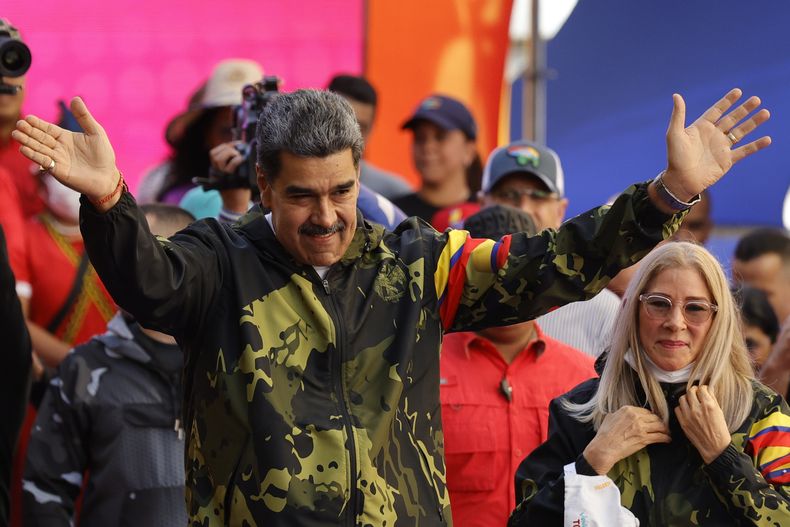 El presidente de Venezuela, Nicolás Maduro, y la primera dama, Cilia Flores, saludan a partidarios del gobierno durante un acto para conmemorar el aniversario del golpe de Estado de 1958 que derrocó al dictador Marcos Pérez Jimenez en Caracas, Venezuela, el 23 de enero de 2024. (AP Foto/Jesus Vargas)