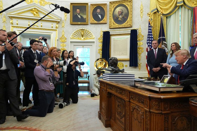 El presidente Donald Trump, sentado a la derecha, señala a los periodistas mientras habla durante un acto sobre atención sanitaria en el Despacho Oval de la Casa Blanca, el viernes 18 de septiembre de 2026, en Washington. (AP Foto/Jacquelyn Martin)
