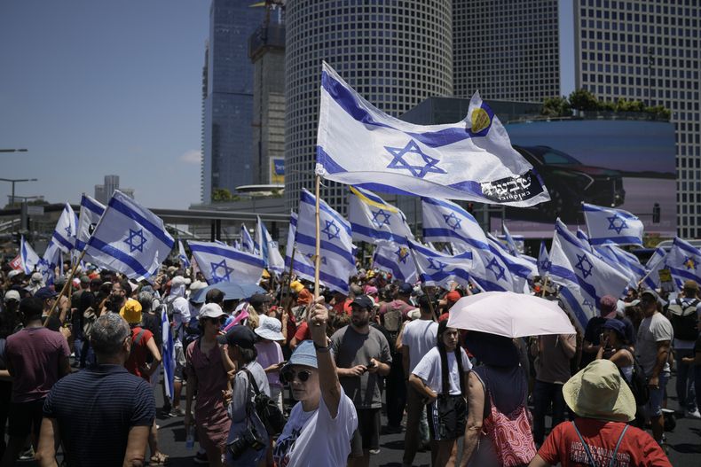 Manifestantes ondean banderas israelíes durante una protesta a los nueve meses del inicio de la guerra en Gaza, en la que reclaman la liberación de los rehenes retenidos en la Franja de Gaza por el grupo armado Hamás, en Tel Aviv, Israel, el domingo 7 de julio de 2024. (AP Foto/Leo Correa)