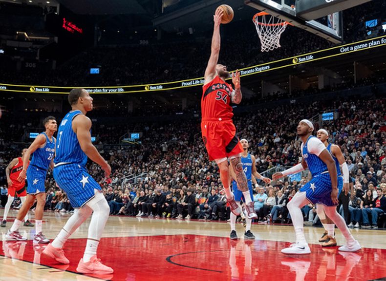 Sandro Mamukelashvili (54), de los Raptors de Toronto, anota entre la defensiva completa del Magic de Orlando durante la primera mitad del juego de baloncesto de la NBA, el domingo 29 de marzo de 2026, en Toronto. (Frank Gunn/The Canadian Press via AP)