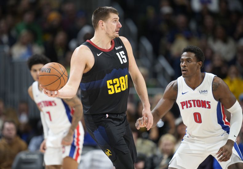 Nikola Jokic (15), pívot de los Nuggets de Denver, busca pasar el balón, ante la presión defensiva de Jalen Duren (0), de los Pistons de Detroit, durante la segunda mitad del juego de baloncesto de la NBA, el domingo 7 de enero de 2024, en Denver. (AP Foto/David Zalubowski)