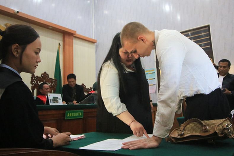 El turista suizo Luzian Andrin Zgraggen, derecha, acusado de insultar el sagrado Día del Silencio del hinduismo balinés en publicaciones en redes sociales, consulta con su abogada durante la audiencia de sentencia en la corte de distrito de Denpasar, Bali, Indonesia, el jueves 20 de agosto de 2026. (Foto AP)