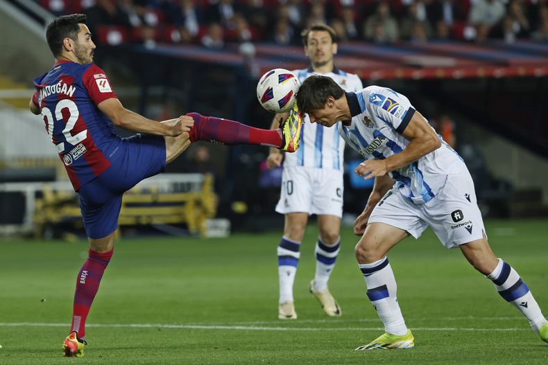 Ilkay Gundogan (izquierda) del Barcelona y Robin Le Normand de la Real Sociedad pugnan por un balón en el partido de la Liga española, el lunes 13 de mayo de 2024, en Barcelona. (AP Foto/Joan Monfort)