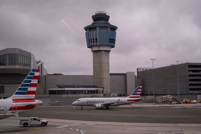 Un avión de American Eagle pasa delante de la torre de control de tráfico aéreo de la Administración Federal de Aviación en el aeropuerto LaGuardia, el domingo 9 de noviembre de 2025, en Queens, Nueva York. (AP Foto/Adam Gray)