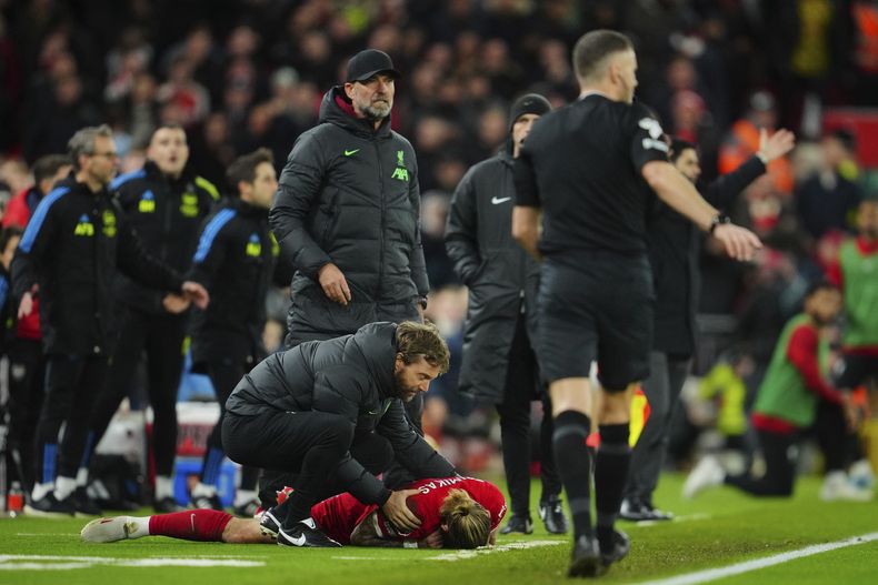Kostas Tsimikas del Liverpool se queja del dolor tras una tacleada de Bukayo Saka del Arsenal y golpearse contra el técnico Jürgen Klopp en el encuentro de la Liga Premier el sábado 23 de diciembre del 2023. (AP Foto/Jon Super)