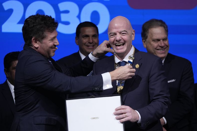 El presidente de CONMEBOL, Alejandro Domínguez, a la izquierda, condecora al presidente de FIFA, Giovanni Infantino, durante el Congreso de la entidad sudamericana en Luque, Paraguay, jueves 11 abril, 2024. (AP Foto/Jorge Saenz)
