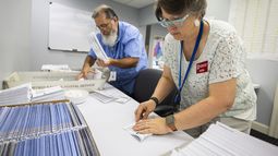 Dawn Stephens y Duane Taylor preparan boletas para votar que serán enviadas por correo postal, en la Junta Electoral del condado Mecklenburg, en Charlotte, Carolina del Norte, el 5 de septiembre de 2024. (AP Foto/Nell Redmond)