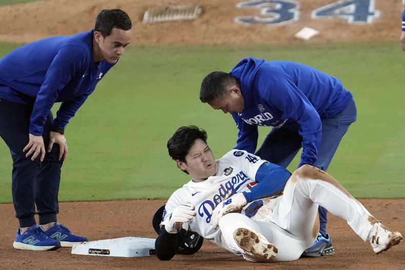 Shohei Ohtani, centro, de los Dodgers de Los Ángeles, reacciona tras lesionarse al intentar robar la segunda base contra los Yankees de Nueva York durante la séptima entrada del Juego 2 de la Serie Mundial de béisbol, el sábado 26 de octubre de 2024, en Los Ángeles. (AP Foto/Julio Cortez)