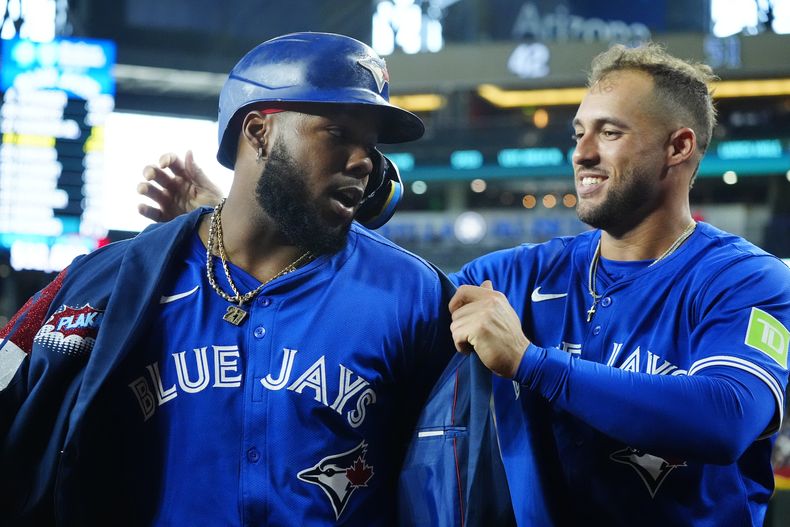 El dominicano de los Azulejos de Toronto, Vladimir Guerrero Jr. (izquierda), celebra su cuadrangular ante los Diamondbacks de Arizona, junto a su compañero de equipo, George Springer durante la séptima entrada del juego de béisbol, el domingo 14 de julio de 2024, en Phoenix. (AP Foto/Ross D. Franklin)