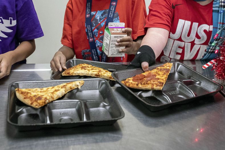ARCHIVO - Estudiantes de segundo grado seleccionan sus comidas durante el almuerzo en la cafetería, el 12 de diciembre de 2022, en una escuela primaria en Scottsdale, Arizona. Más estudiantes en las escuelas que sirven a las comunidades de bajos ingresos serán elegibles para recibir el desayuno y el almuerzo sin costo alguno en virtud de un cambio de regla anunció el martes, 26 de septiembre de 2023, por el Departamento de Agricultura de Estados Unidos. (AP Foto/Alberto Mariani, Archivo)
