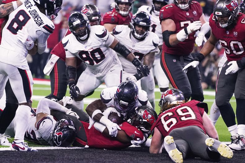 Rachaad White, abajo en el centro, running back de los Buccaneers de Tampa Bay, anota el touchdown de la victoria mientras C.J. Gardner-Johnson (8), Sheldon Rankins (90) y otros jugadores de los Texans de Houston observan a segundos del final del partido de la NFL del lunes 15 de septiembre de 2025, en Houston, Texas. (AP Foto/Eric Christian Smith)