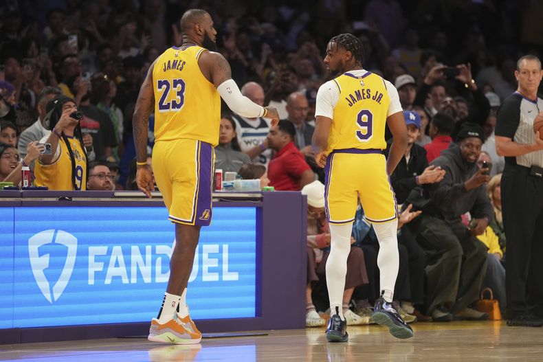 LeBron James, de los Lakers de Los Ángeles, y su hijo Bronny, caminan en la cancha durante el encuentro del martes 22 de octubre de 2024, ante los Timberwolves de Minnesota (AP Foto/Eric Thayer)