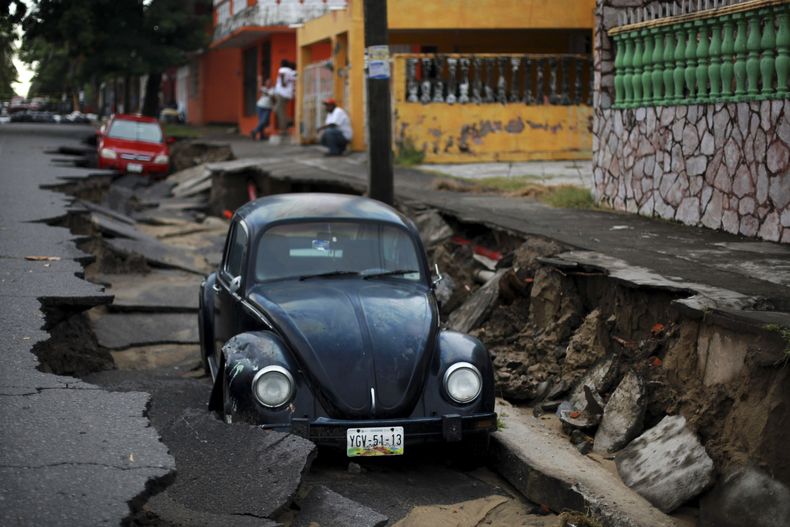 Un par de autos yacen en una porci&oacute;n de una calle hundida por las intensas lluvias en el puerto de Veracruz, M&eacute;xico, el martes 2 de septiembre de 2014. Los estados del Golfo de M&eacute;xico esperan m&aacute;s lluvias provocadas por la torme