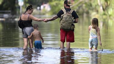 ARCHIVO - Dustin Holmes, segundo de derecha a izquierda, toma la mano de su novia, Hailey Morgan, mientras vuelven a su casa inundada, con sus hijos Aria Skye Hall, de 7 años, derecha, y Kyle Ross, de 4, tras el paso del huracán Helene, el 27 de septiembre de 2024, en Crystal River, Florida. (AP Foto/Phelan M. Ebenhack, Archivo)