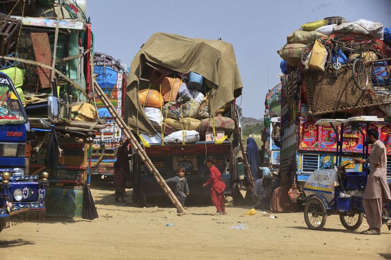 ARCHIVO - Niños refugiados afganos juegan junto a camiones cargados con las pertenencias de su familia mientras esperan regresar a Afganistán por una carretera en Landi Kotal, Pakistán, el 9 de abril de 2025. (AP Foto/Muhammad Sajjad, Archivo)