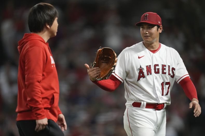 El japonés Shohei Ohtani habla con el intérprete Ippei Mizuhara al abandonar el montículo en la sexta entrada del juego ante los Astros de Houston, e viernes 14 de julio de 2023 (AP Foto/Ashley Landis)